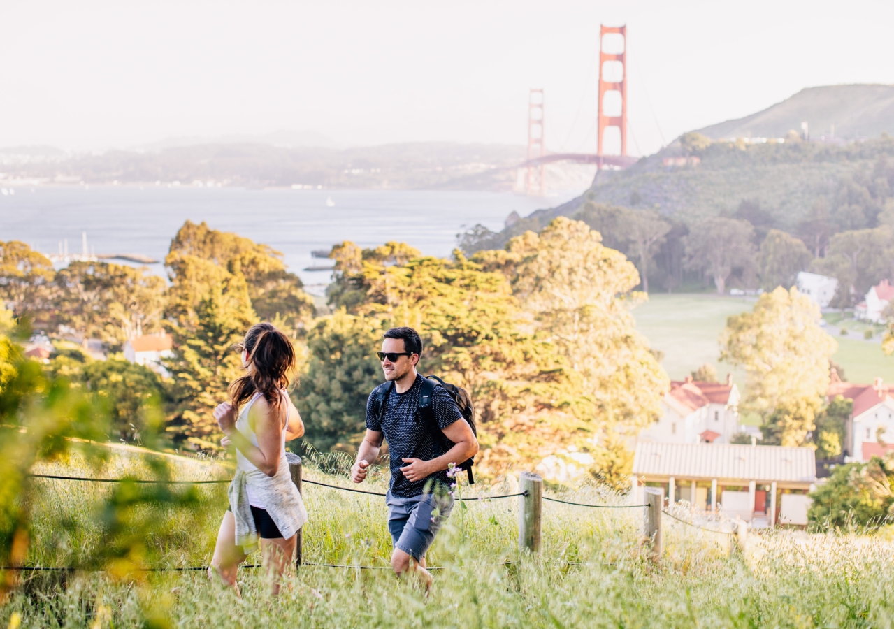 couple hiking golden gate and property in background