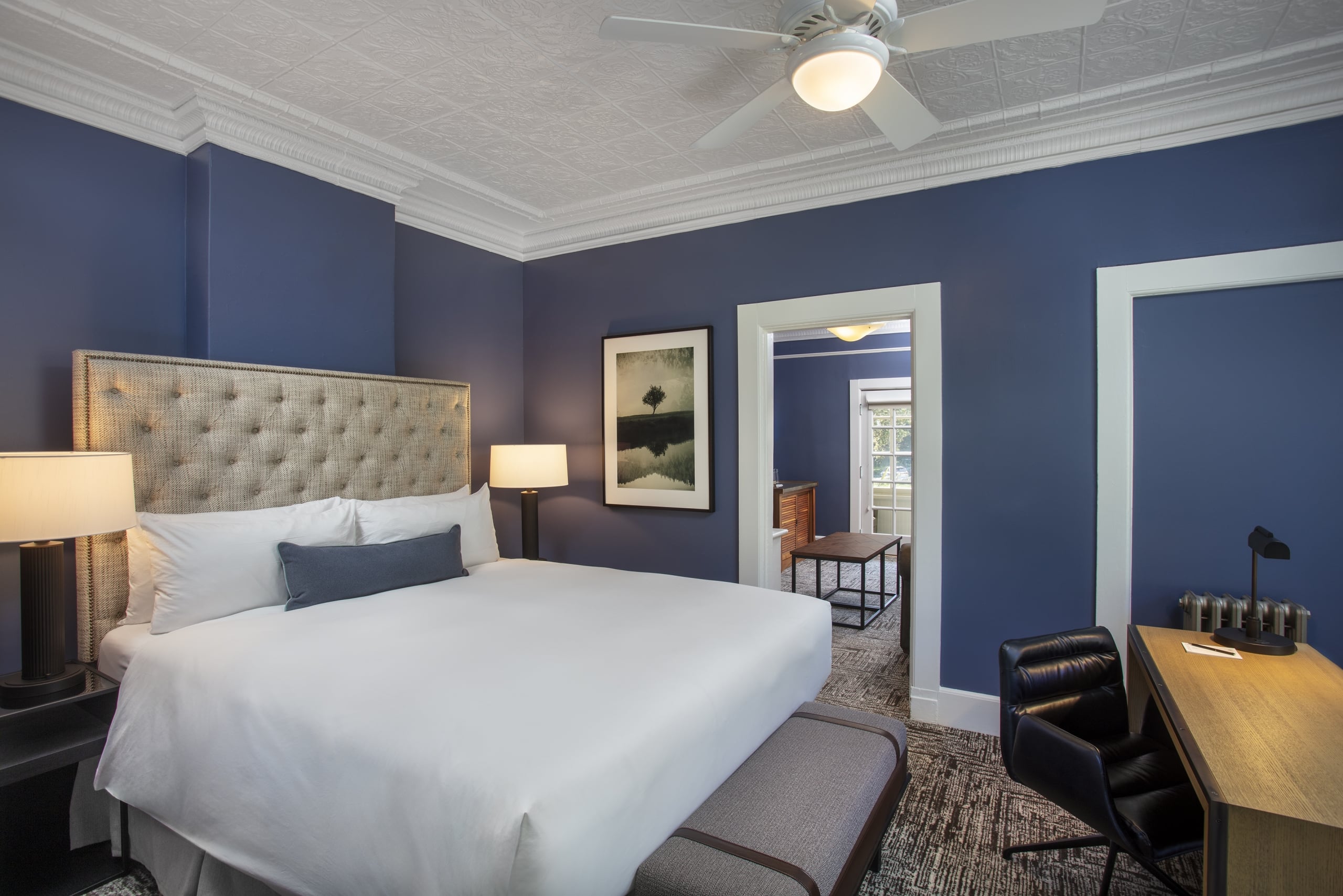 historic room with king bed, desk and view into sitting area