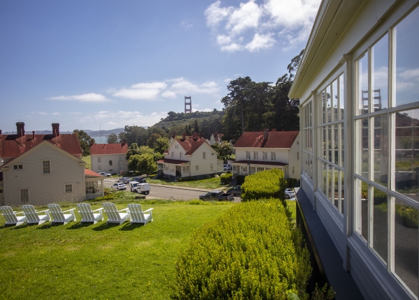Lawn area with multiple white chairs overlooking buildings at Cavallo Point and the Golden Gate Bridge.