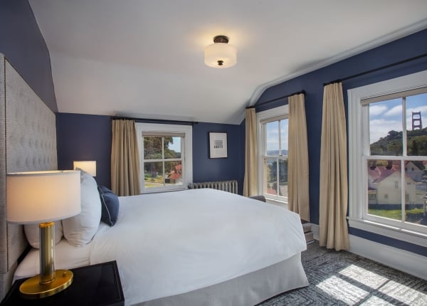 Upstairs bedroom with white bed and windows overlooking the Golden Gate Bridge.