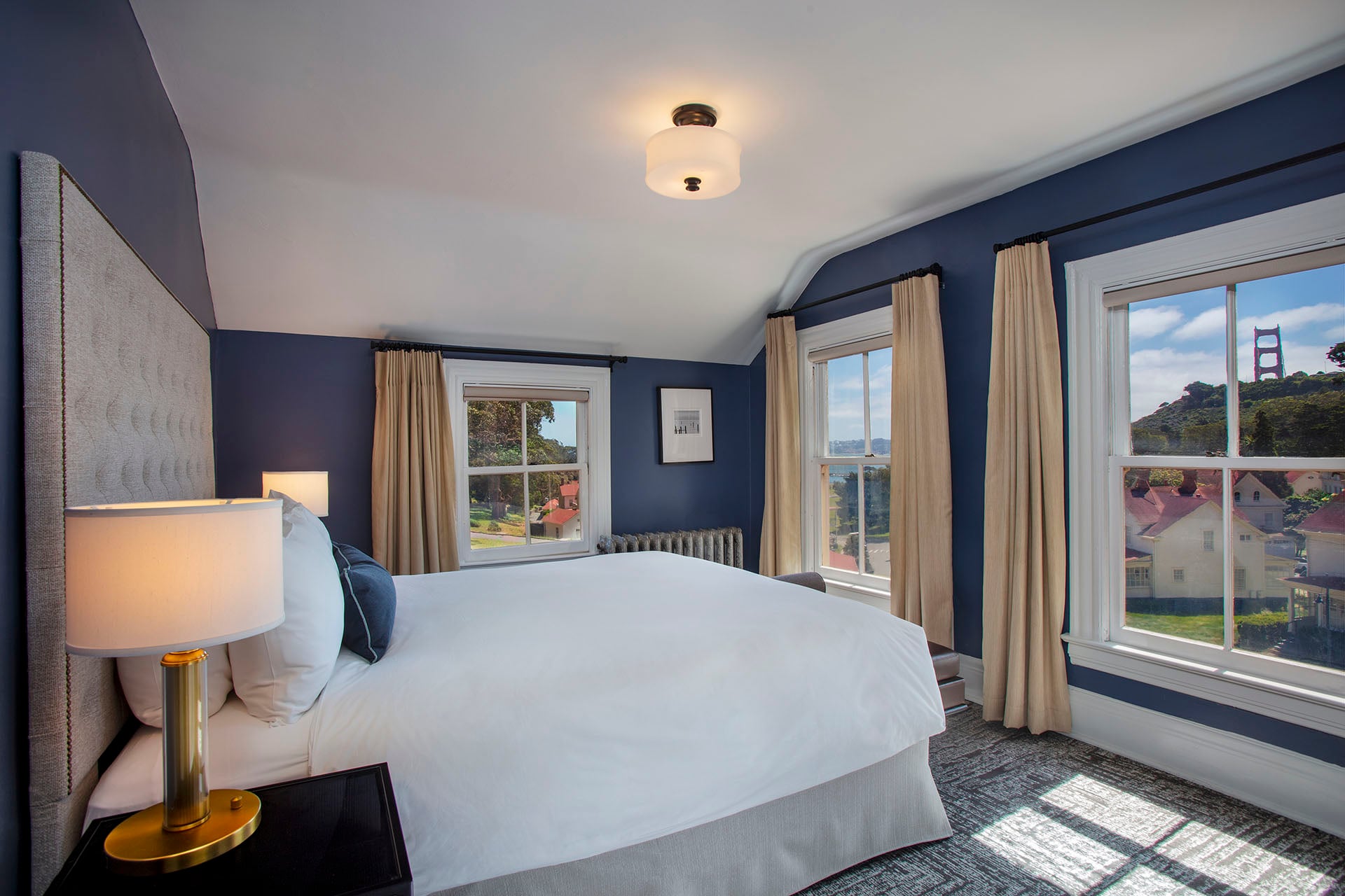 Upstairs bedroom with white bed and windows overlooking the Golden Gate Bridge.