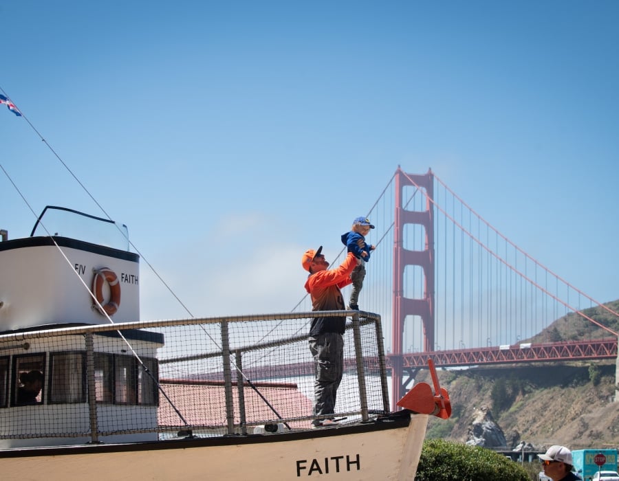 Father holding son up on boat by Golden Gate