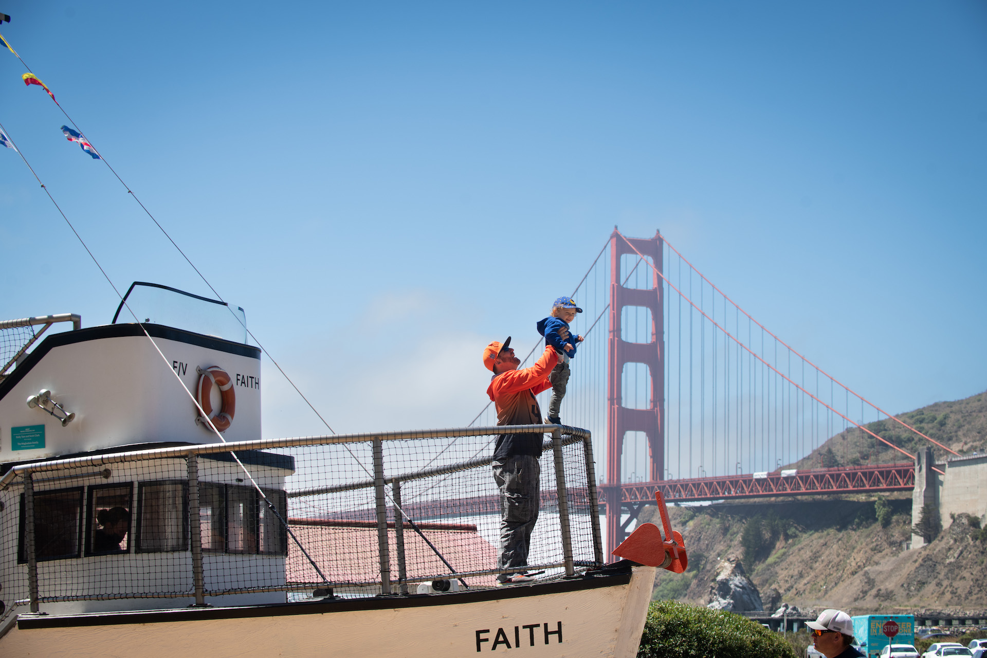 Father holding son up on boat by Golden Gate