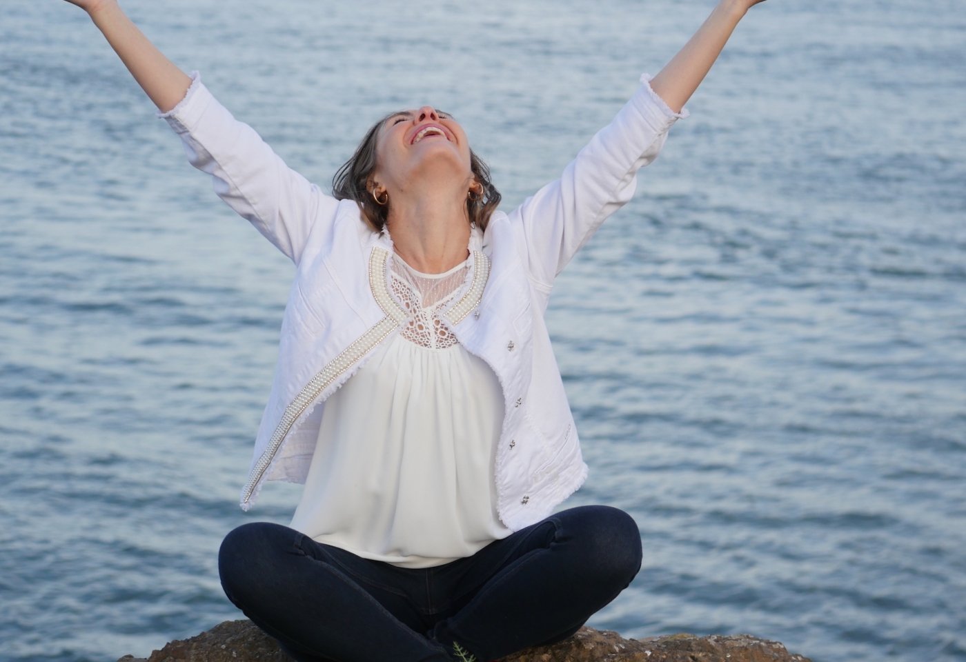 woman sitting by water hands outstretched