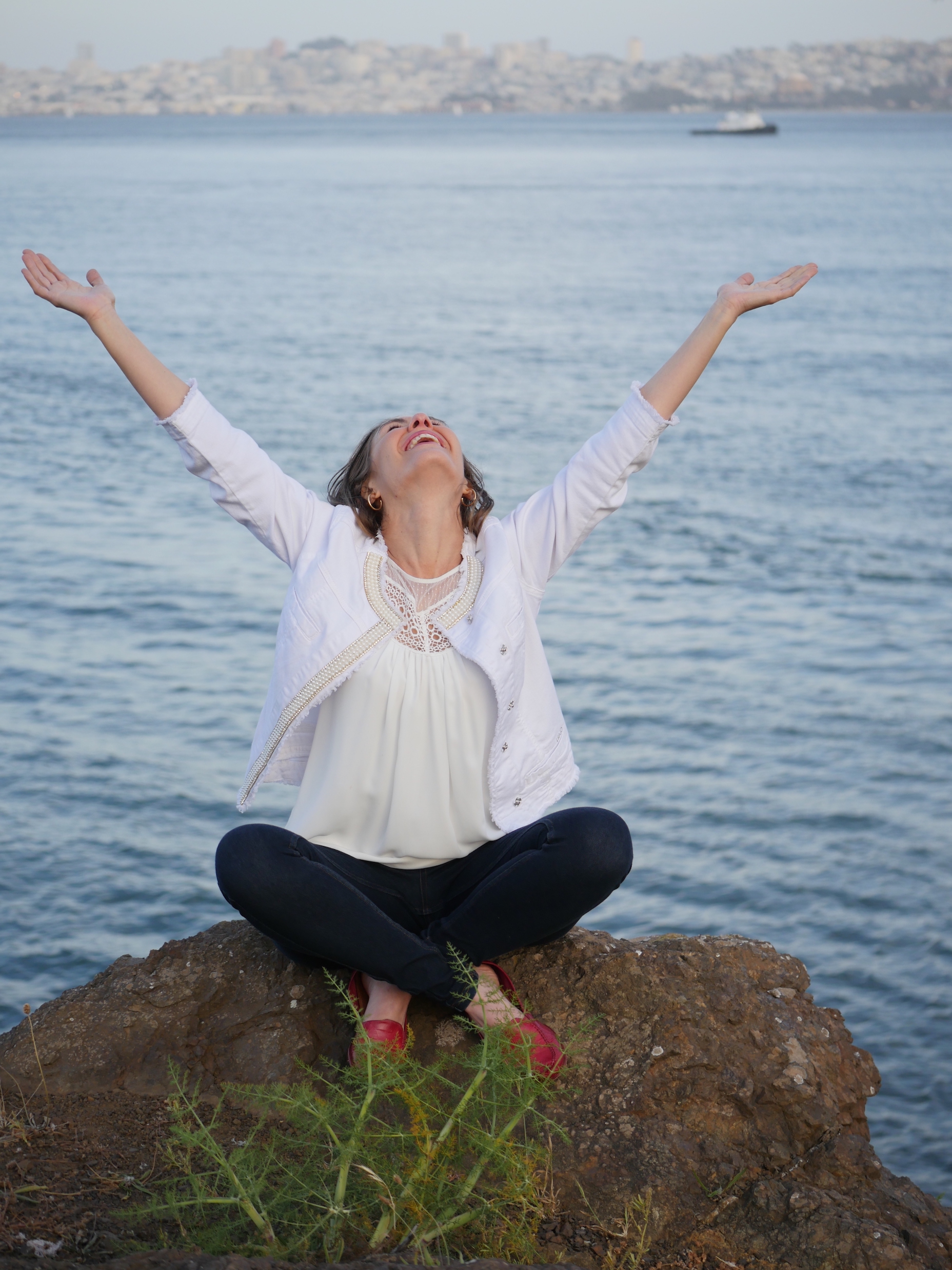 woman sitting by water hands outstretched