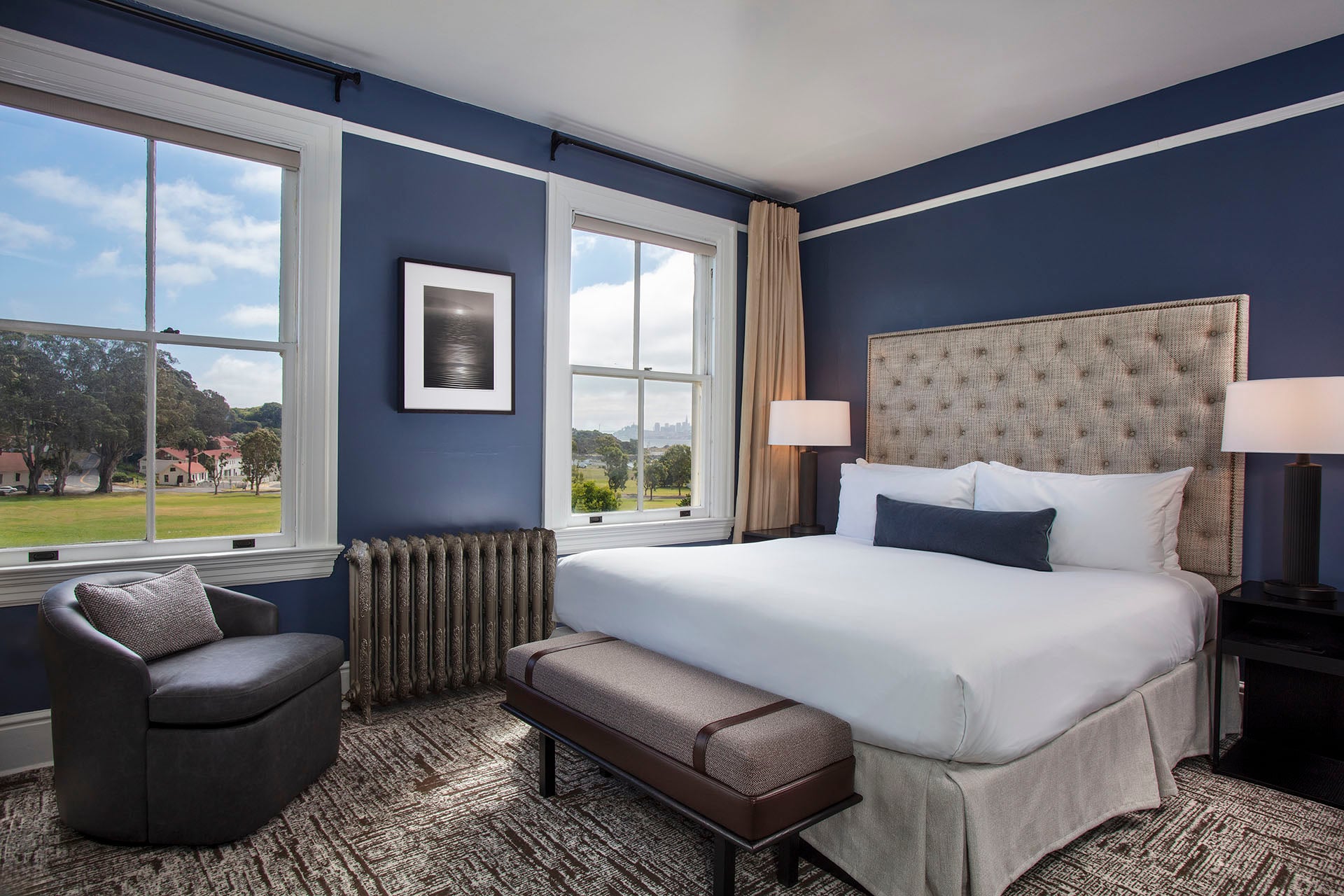 Historic King room with a white bed, chair and a view of Cavallo Point and downtown San Francisco