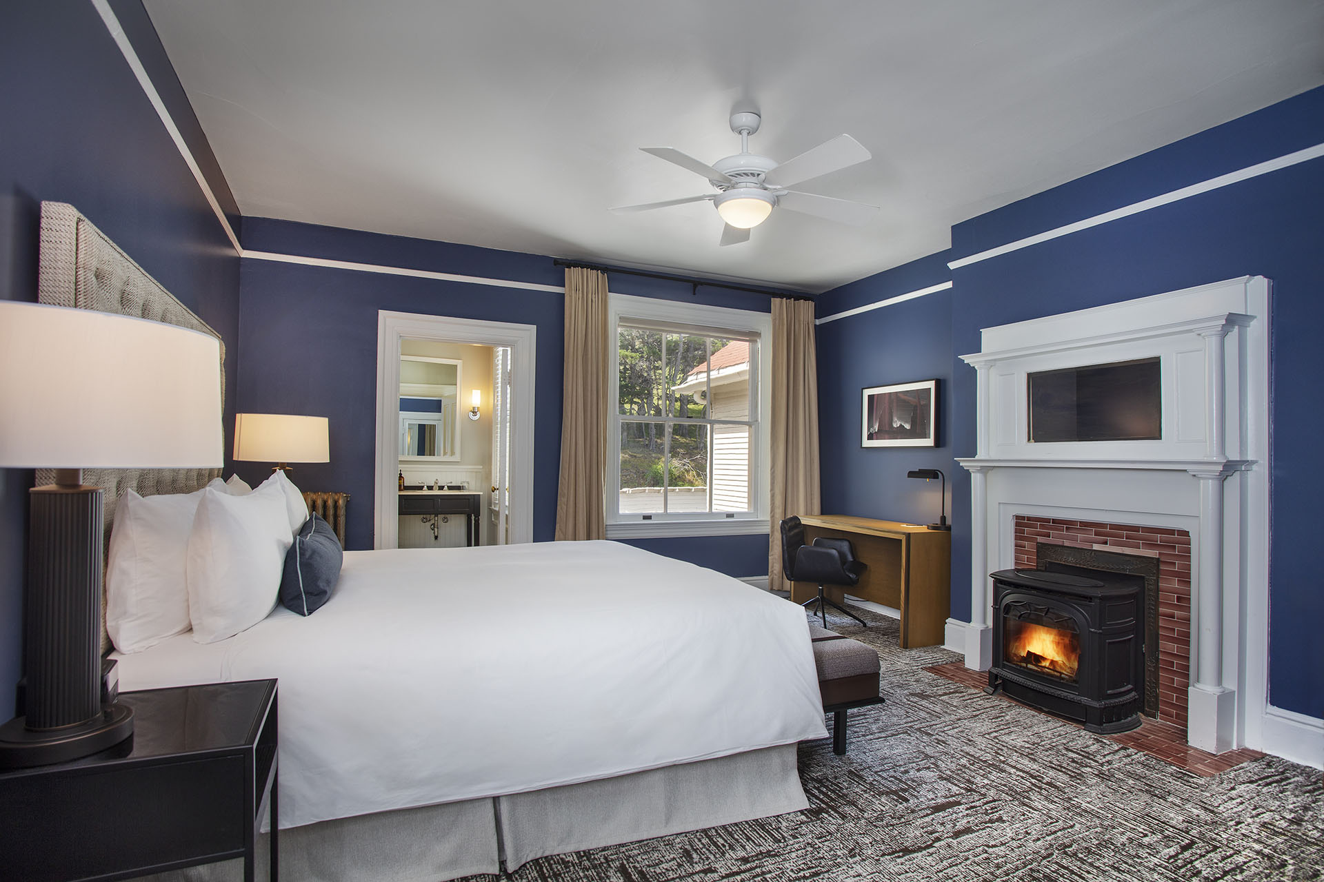 Historic King room with a fireplace, desk, bed and a view of the building and hillside