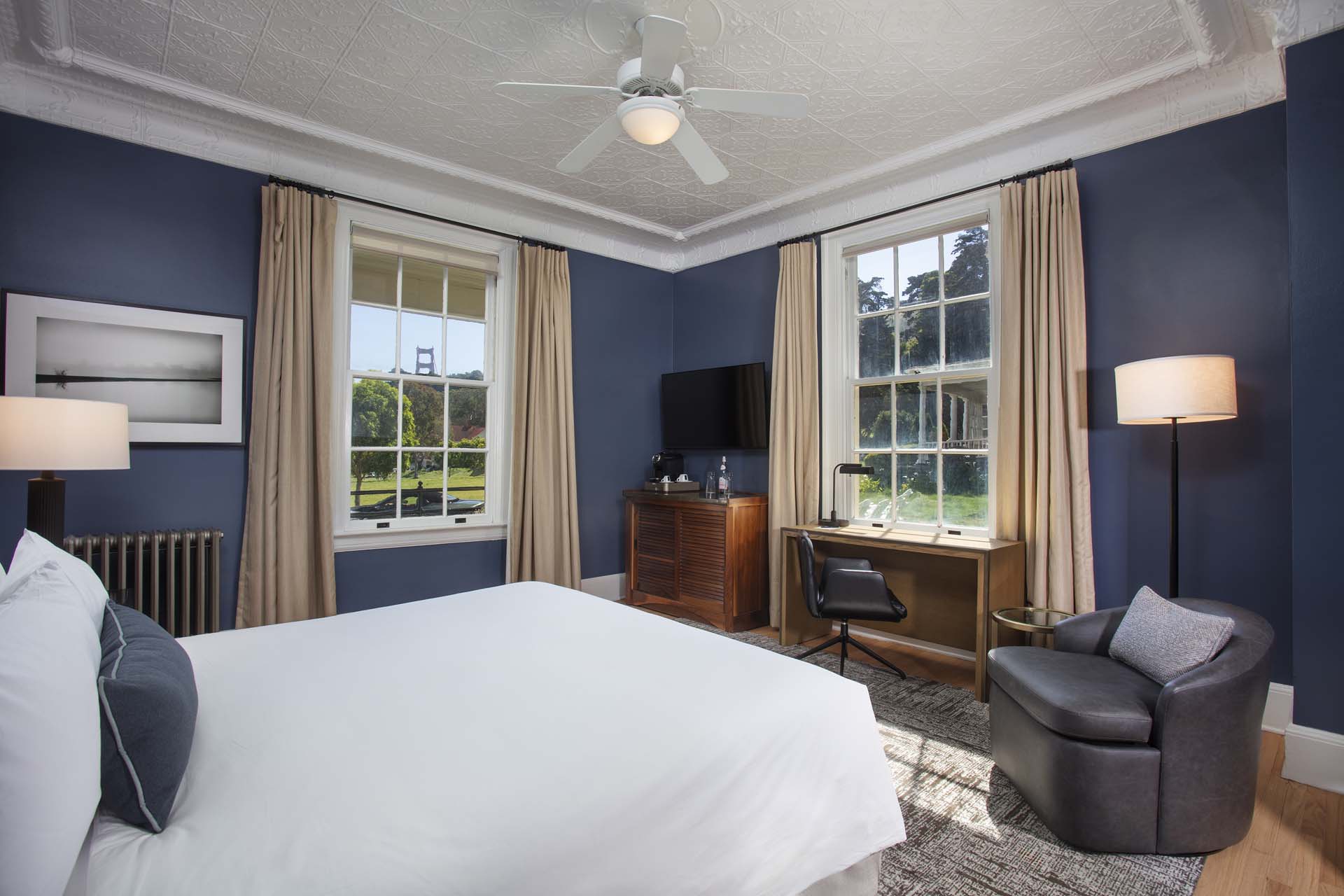Guestroom with a king bed, desk, chair, TV and view of the Golden Gate Bridge