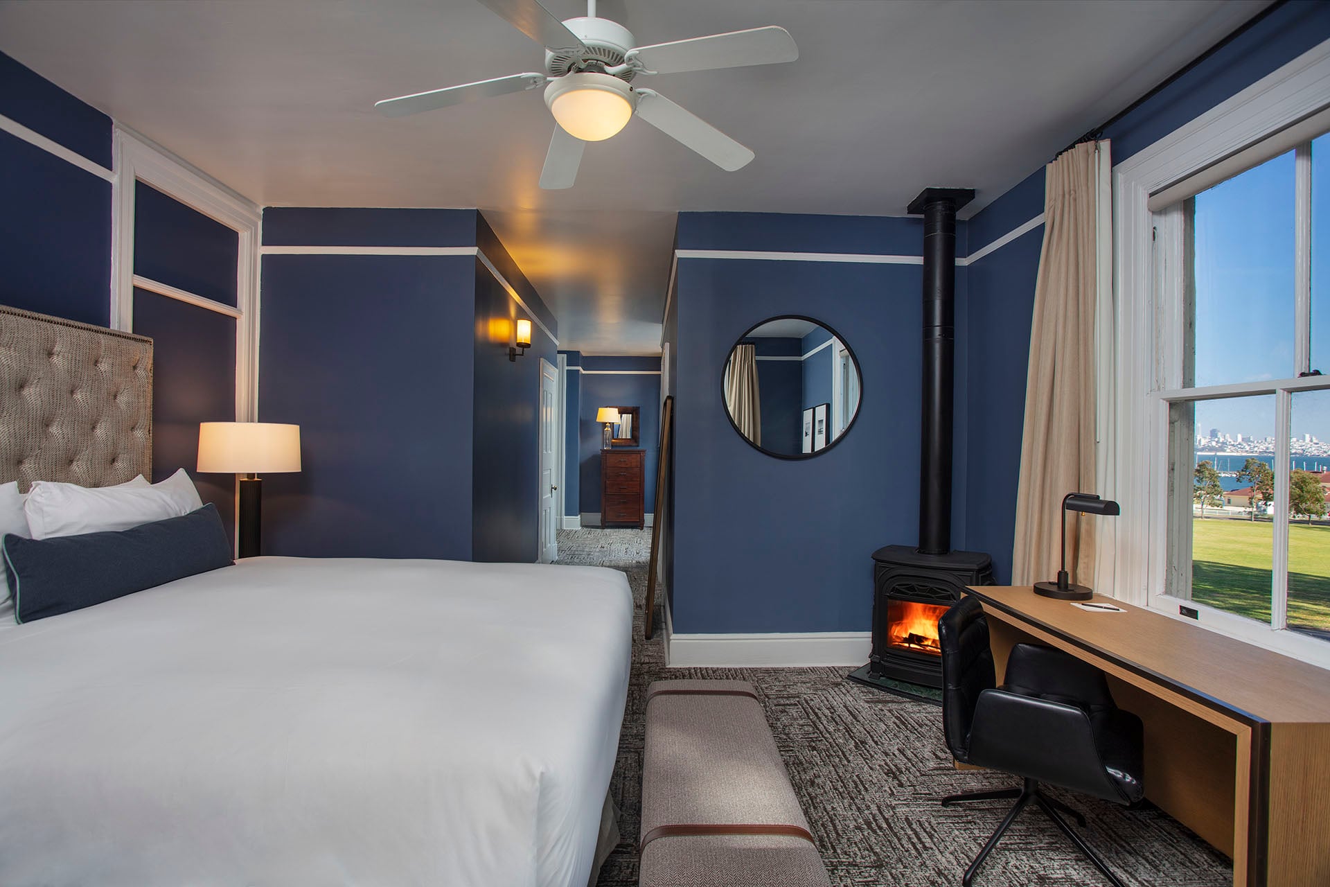 Historic bedroom with King bed, desk, fireplace and hallway with view of San Francisco skyline