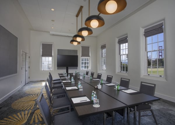 Meeting room with a boardroom table, view of the Golden Gate Bridge and a TV screen.