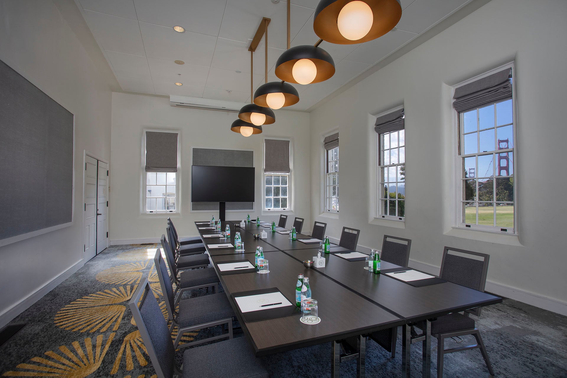 Meeting room with a boardroom table, view of the Golden Gate Bridge and a TV screen.